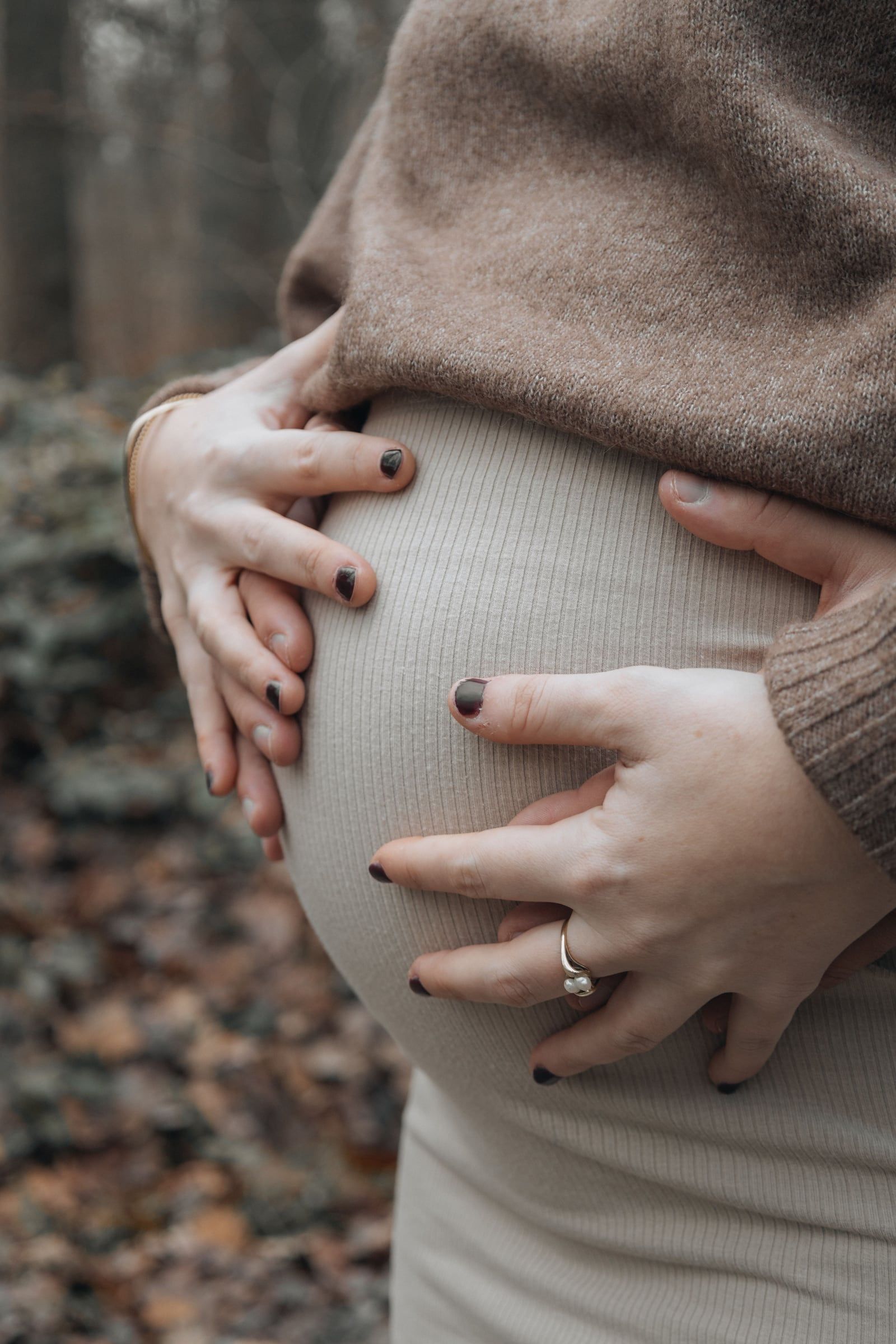 Duas mãos sobre uma barriga de grávida.